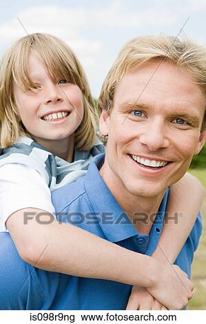 Stock Image - Father giving son a piggyback. Fotosearch