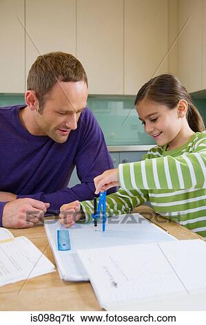 Stock Image - Father helping his daughter with homework. Fotosearch