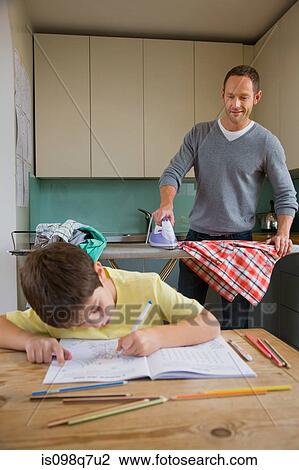 Stock Image - Father ironing and son colouring in. Fotosearch