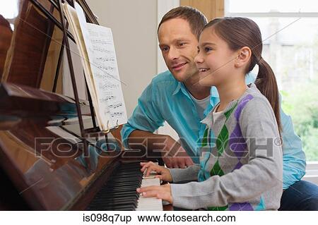Stock Photography - Father teaching daughter how to play the piano. Fotosearch