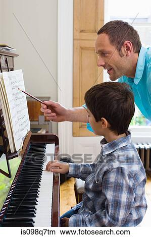 Picture - Father teaching son how to play the piano. Fotosearch