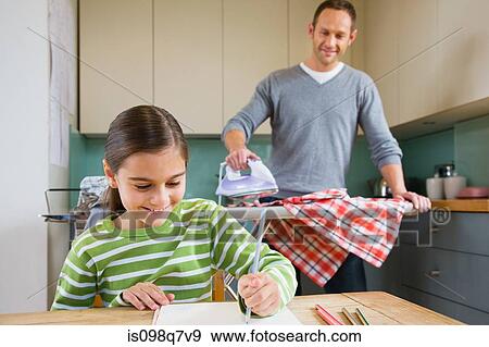 Stock Photo - Father watching daughter colouring in. Fotosearch