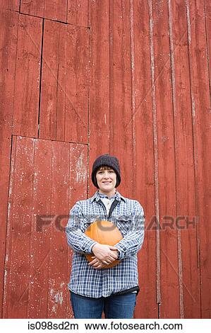 Picture - Female farmer holding a pumpkin. Fotosearch