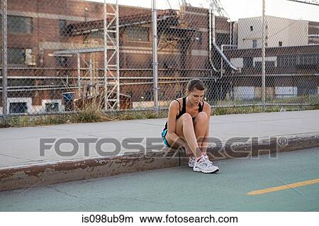 Picture - Female runner sitting on sidewalk. Fotosearch
