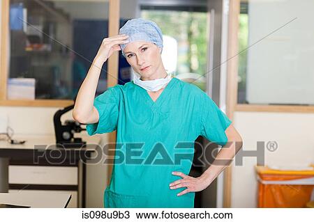 Stock Image - Female surgeon looking stressed. Fotosearch