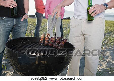 Stock Image - Friends having a barbecue. Fotosearch