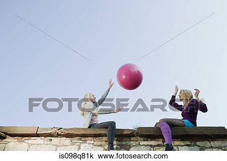 Stock Image - Friends throwing a ball. Fotosearch