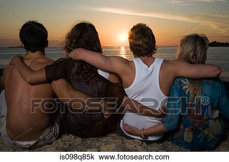 Friends watching the sunset by sea View Large Photo Image Stock Image - Friends watching the sunset by sea. Fotosearch