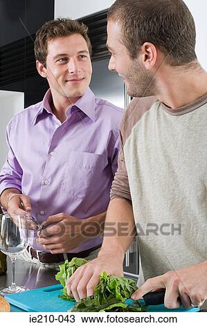 Stock Image - Gay couple in kitchen. Fotosearch