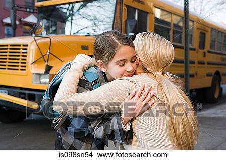 Picture - Girl and mother hugging by school bus. Fotosearch