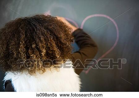 Girl drawing heart on blackboard View Large Photo Image Stock Photograph - Girl drawing heart on blackboard. Fotosearch