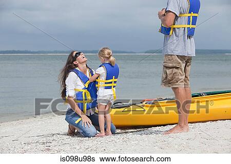 Girl helping mother put on lifejacket for kayaking View Large Photo Image Stock Photograph - Girl helping mother put on lifejacket for kayaking. Fotosearch