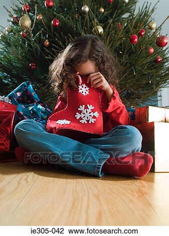 Stock Image - Girl looking in a christmas stocking. Fotosearch