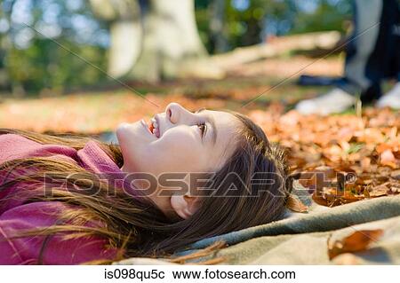 Stock Image - Girl lying on leaves. Fotosearch