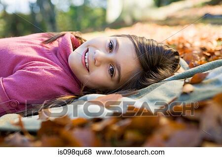 Girl lying on leaves View Large Photo Image Stock Photo - Girl lying on leaves. Fotosearch