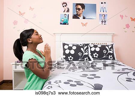 Stock Image - Girl praying in her bedroom. Fotosearch