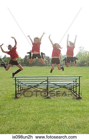 Stock Image - Girl soccer players jumping off bleachers. Fotosearch