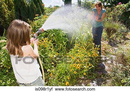 Girl spraying water at mother View Large Photo Image Stock Image - Girl spraying water at mother. Fotosearch