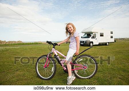 Stock Photo - Girl with a bicycle near caravan. Fotosearch