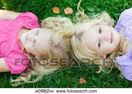 Girls lying on grass View Large Photo Image Stock Photo - Girls lying on grass. Fotosearch