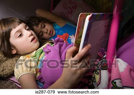 Stock Photo - Girls reading in bed. Fotosearch