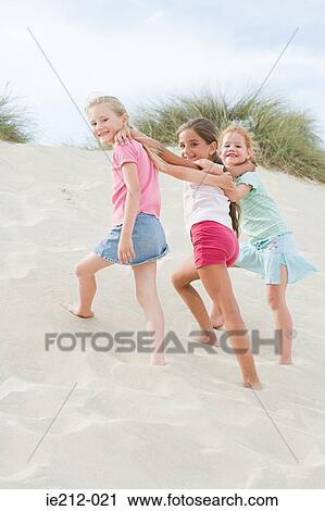 Girls walking up a sand dune View Large Photo Image Stock Image - Girls walking up a sand dune. Fotosearch