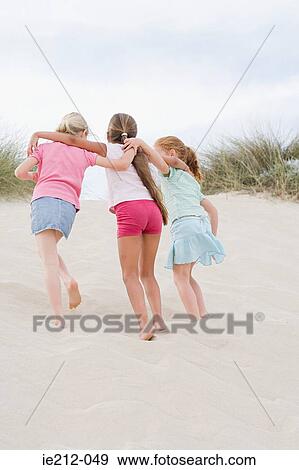 Stock Photo - Girls walking up a sand dune. Fotosearch