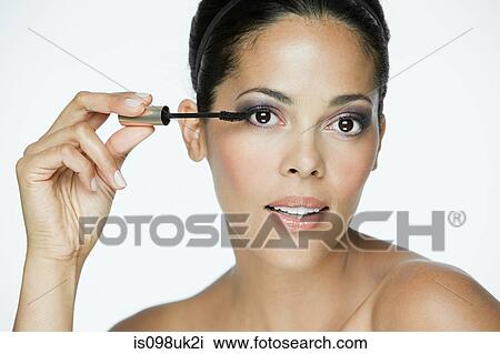 Stock Image - Glamorous woman applying mascara. Fotosearch