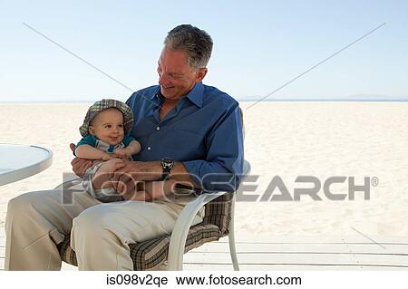 Stock Image - Grandfather sitting with baby grandson. Fotosearch
