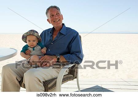Stock Image - Grandfather sitting with baby grandson. Fotosearch