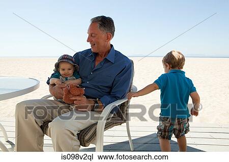 Stock Image - Grandfather sitting with two grandsons. Fotosearch