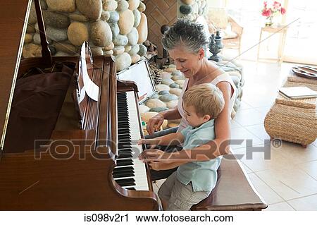 Stock Image - Grandmother and grandson playing the piano. Fotosearch