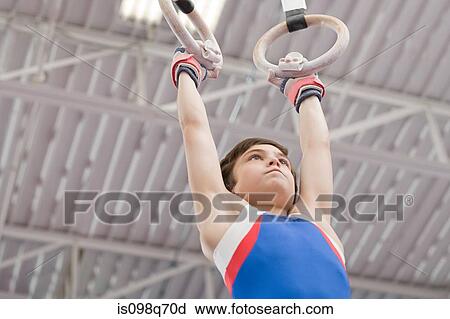 Stock Image - Gymnanast hanging from gymnastic rings. Fotosearch