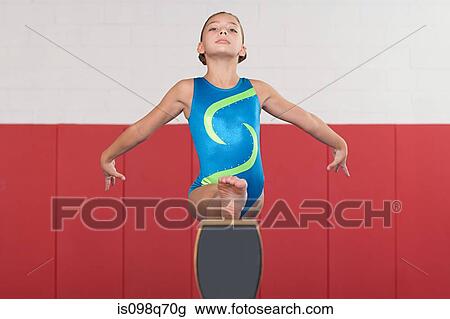 Stock Image - Gymnast doing the splits on a balance beam. Fotosearch