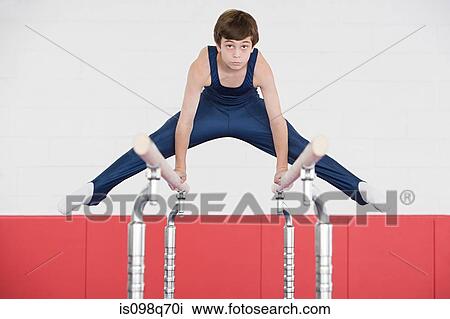 Stock Image - Gymnast doing the splits on parallel bars. Fotosearch