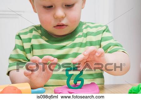 Stock Image - Little boy with modelling clay. Fotosearch