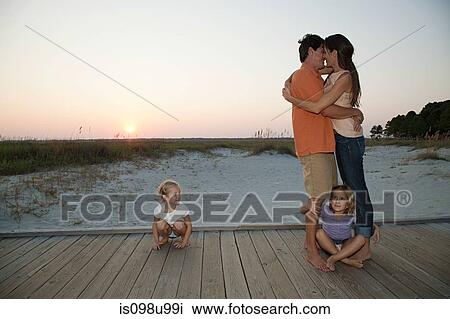 Stock Image - Loving couple and daughters on beach walkway. Fotosearch
