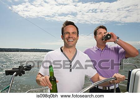 Stock Image - Male friends sailing a boat. Fotosearch