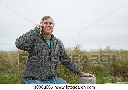 Man at the coast on smartphone View Large Photo Image Stock Photography - Man at the coast on smartphone. Fotosearch