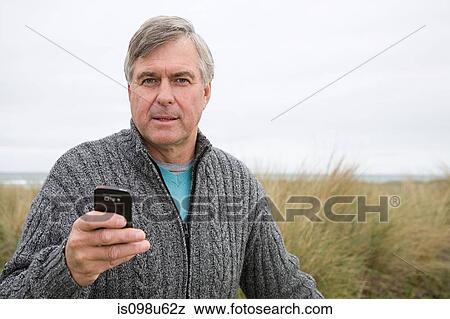 Man at the coast with smartphone View Large Photo Image Stock Photo - Man at the coast with smartphone. Fotosearch