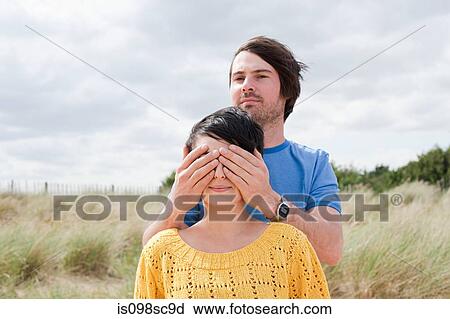 Stock Image - Man covering eyes of girlfriend. Fotosearch