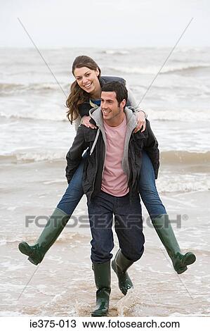 Stock Image - Man giving woman a piggyback. Fotosearch