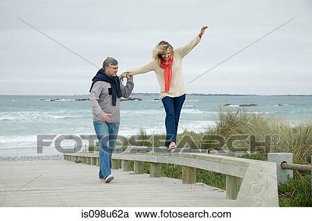 Stock Image - Man helping woman balance on railing. Fotosearch