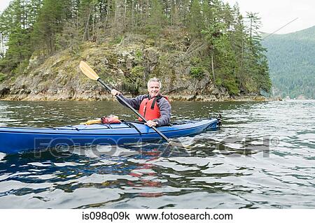 Stock Image - Man kayaking in fjord. Fotosearch