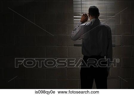 Stock Image - Man looking through blinds. Fotosearch