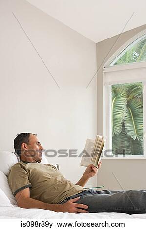 Stock Photo - Man reading a book in bed. Fotosearch