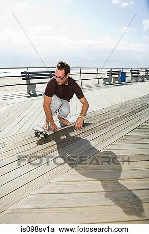 Man skateboarding on boardwalk View Large Photo Image Stock Image - Man skateboarding on boardwalk. Fotosearch