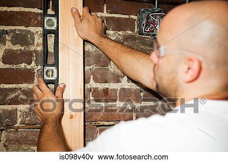 Man using spirit level against brick wall View Large Photo Image Stock Photo - Man using spirit level against brick wall. Fotosearch