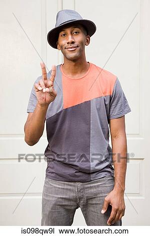 Stock Image - Man wearing fedora and doing peace sign. Fotosearch