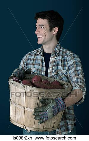 Stock Image - Man with container of potatoes. Fotosearch